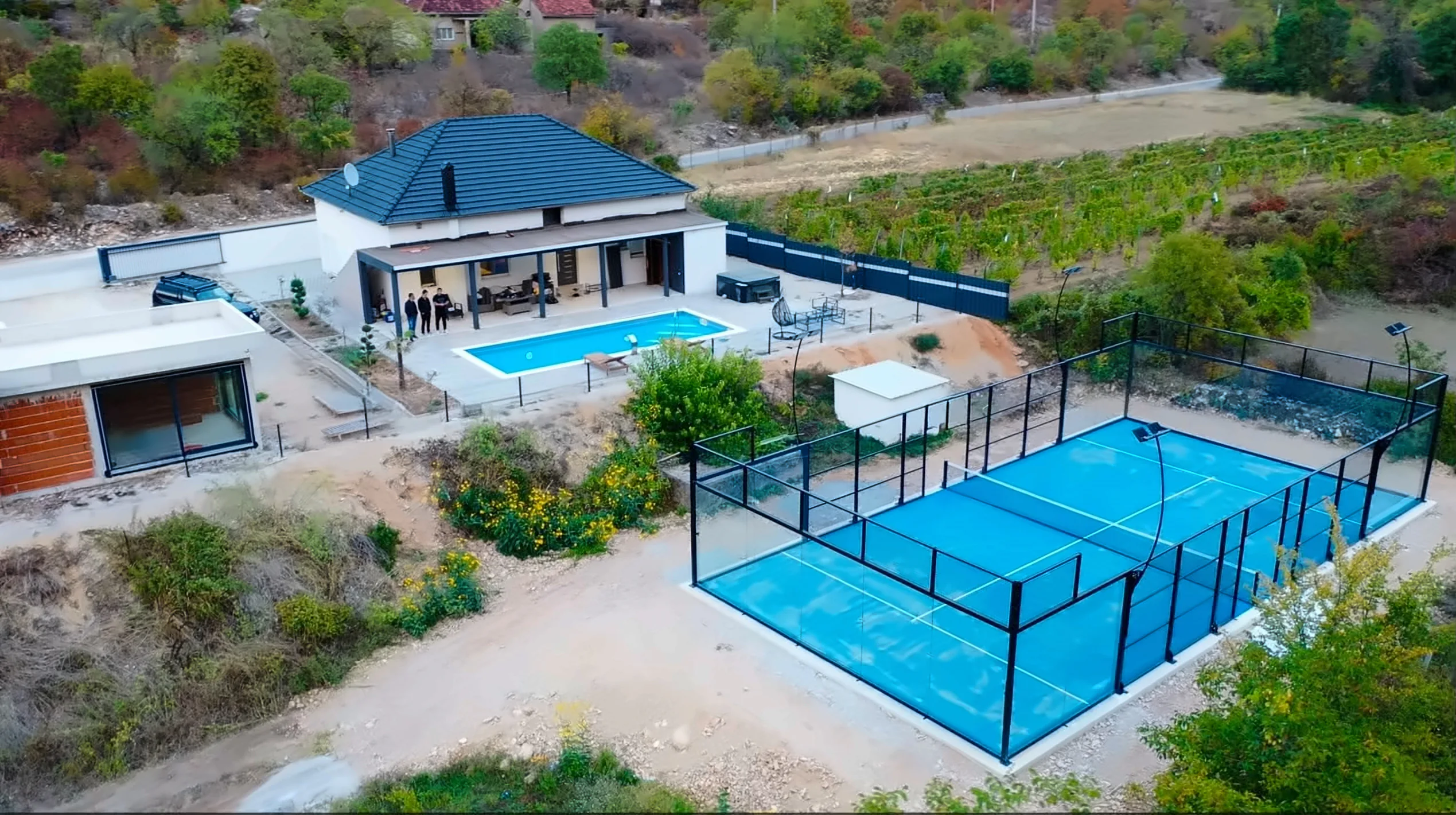Kuća s natkrivenom terasom i bazenom, padel teren i vinograd u pozadini, snimljeno iz zraka